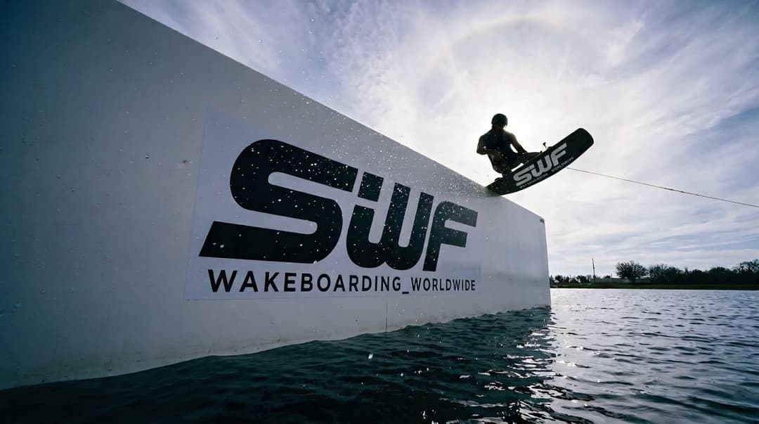Rider SWF qui slide un module en wakepark, en contre-jour, devant le logo SWF Wakeboarding Worldwide
